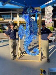 Debris artists pose next to finished seahorse statue