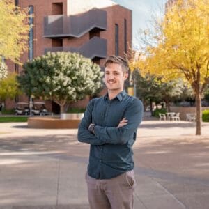 Man stands on ASU campus with crossed hands and smile