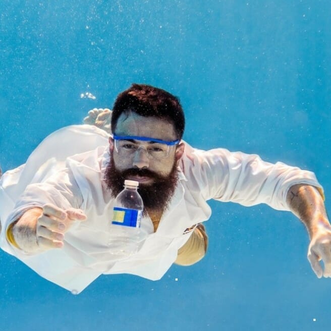 Man swimming underwater grabbing a plastic bottle