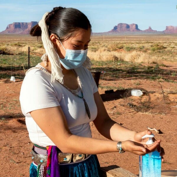 Navajp woman wearing mask and using hand sanitizer