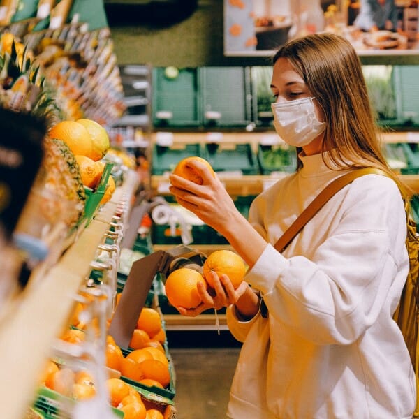 Woman wearing covid mask looking at produce in grocery store