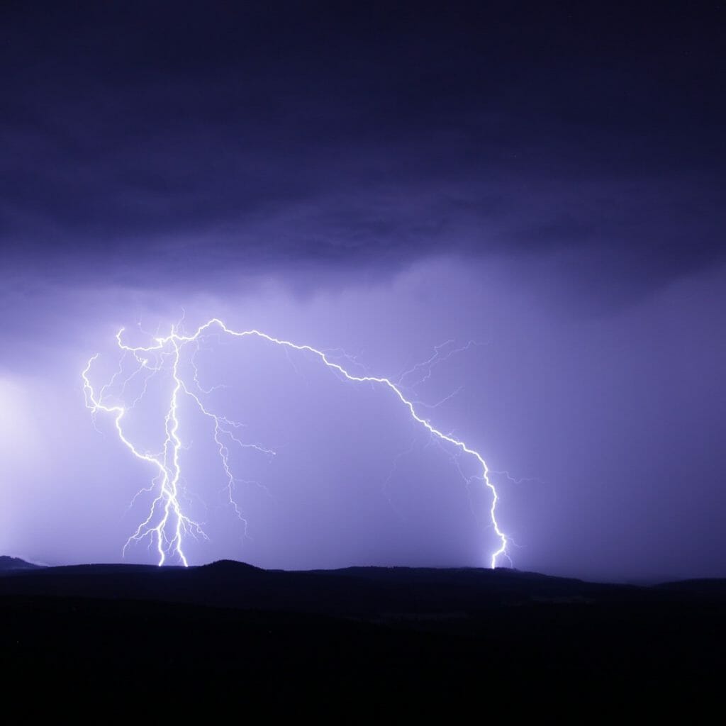 lightning over mountains with purple sky