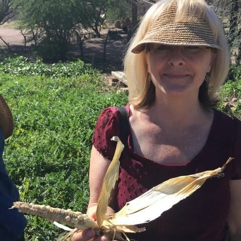 Joni Adamson, wearing a visor and holding an ear of corn.