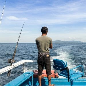 man stands at the back of a fishing boat